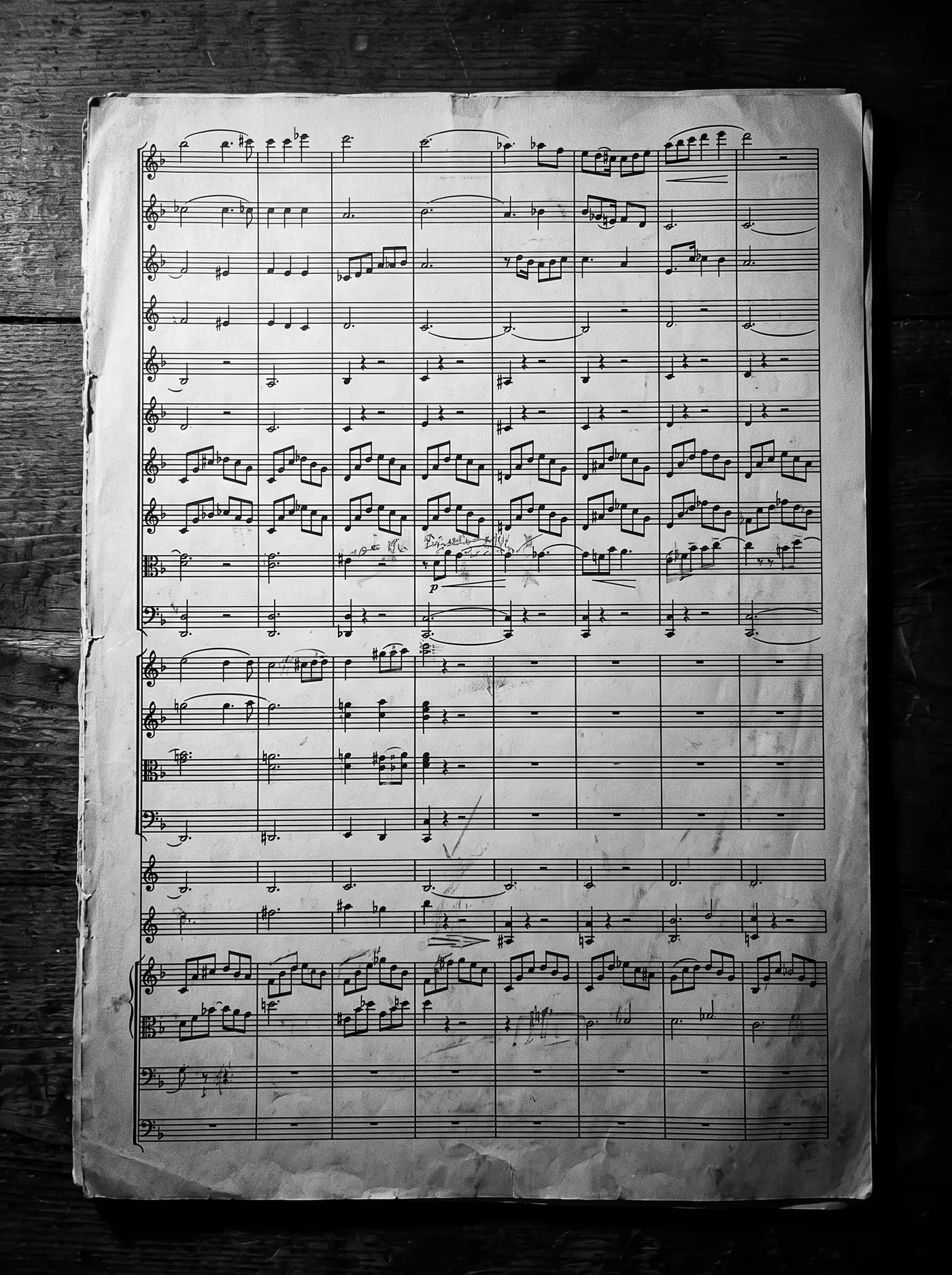 A page of an orchestral score with many stacked staves and pencil corrections